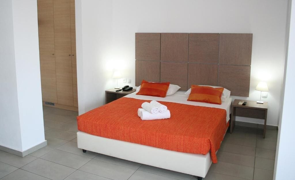 Una habitación de hotel con una cama grande, dos mesitas de noche y un cabecero de madera.