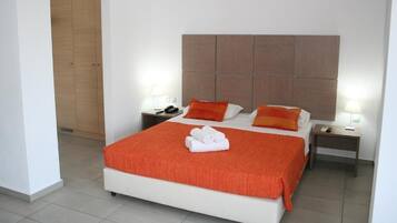 Una habitación de hotel con una cama grande, dos mesitas de noche y un cabecero de madera.