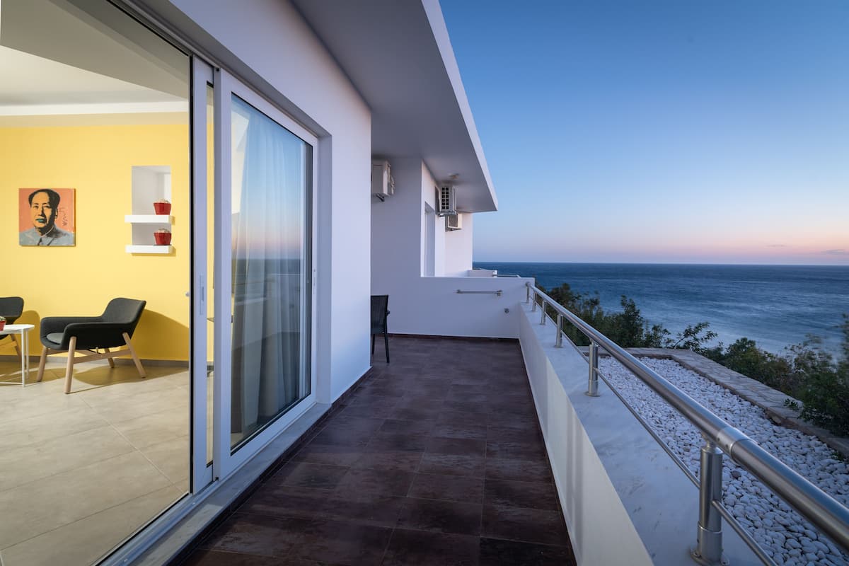 Un balcon moderne avec une porte vitrée, une chaise, une petite table et un tableau accroché au mur.