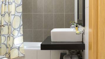 Une salle de bain avec un lavabo blanc, un plan de toilette noir, un miroir et un porte-serviettes.