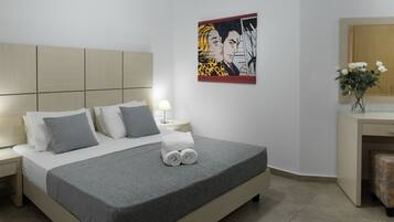 Una habitación de hotel moderna con una cama grande, una mesita de noche con una lámpara, un cuadro en la pared y un escritorio con un florero.