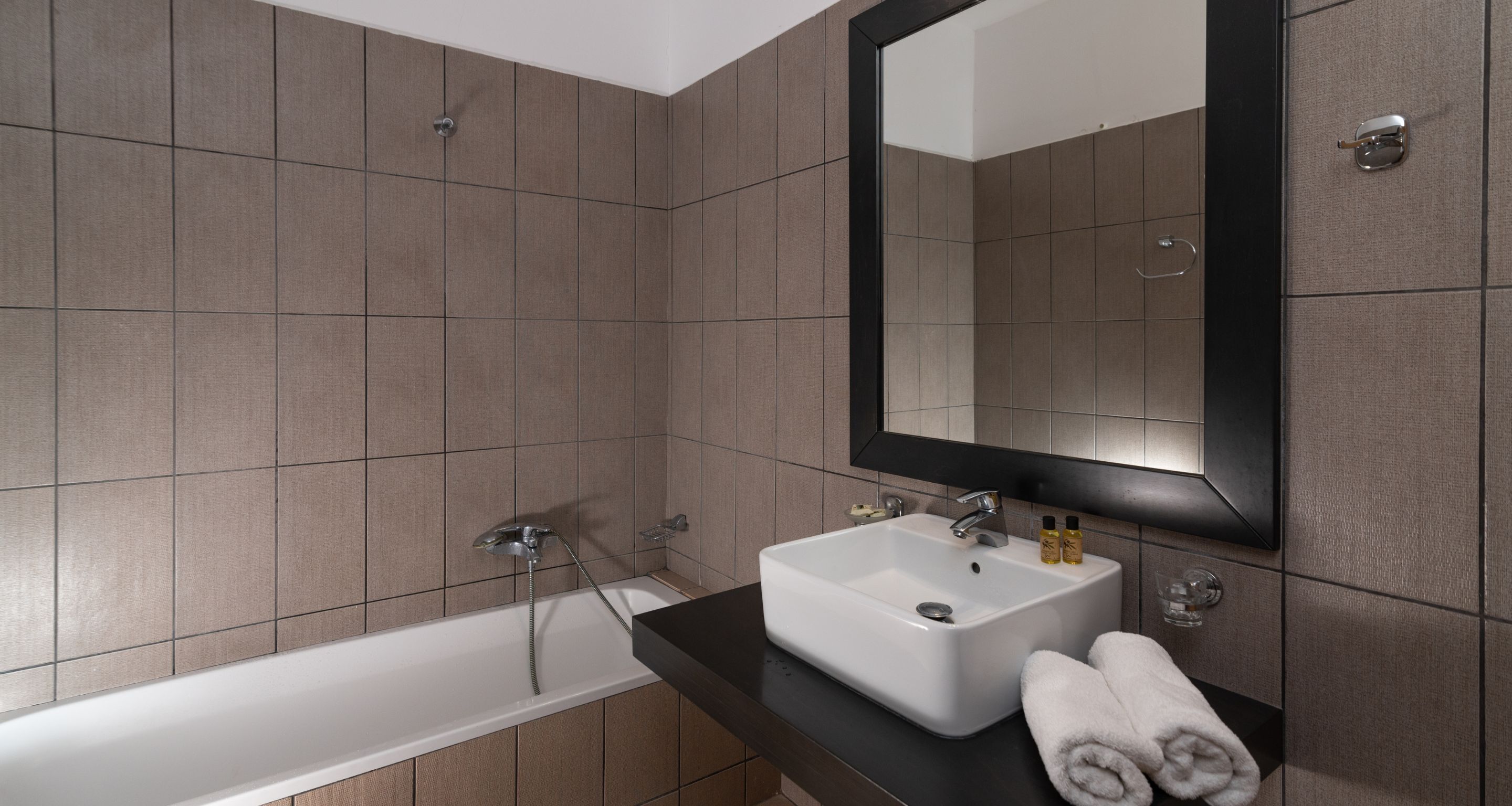 Un baño moderno con bañera, lavamanos y un espejo grande.
