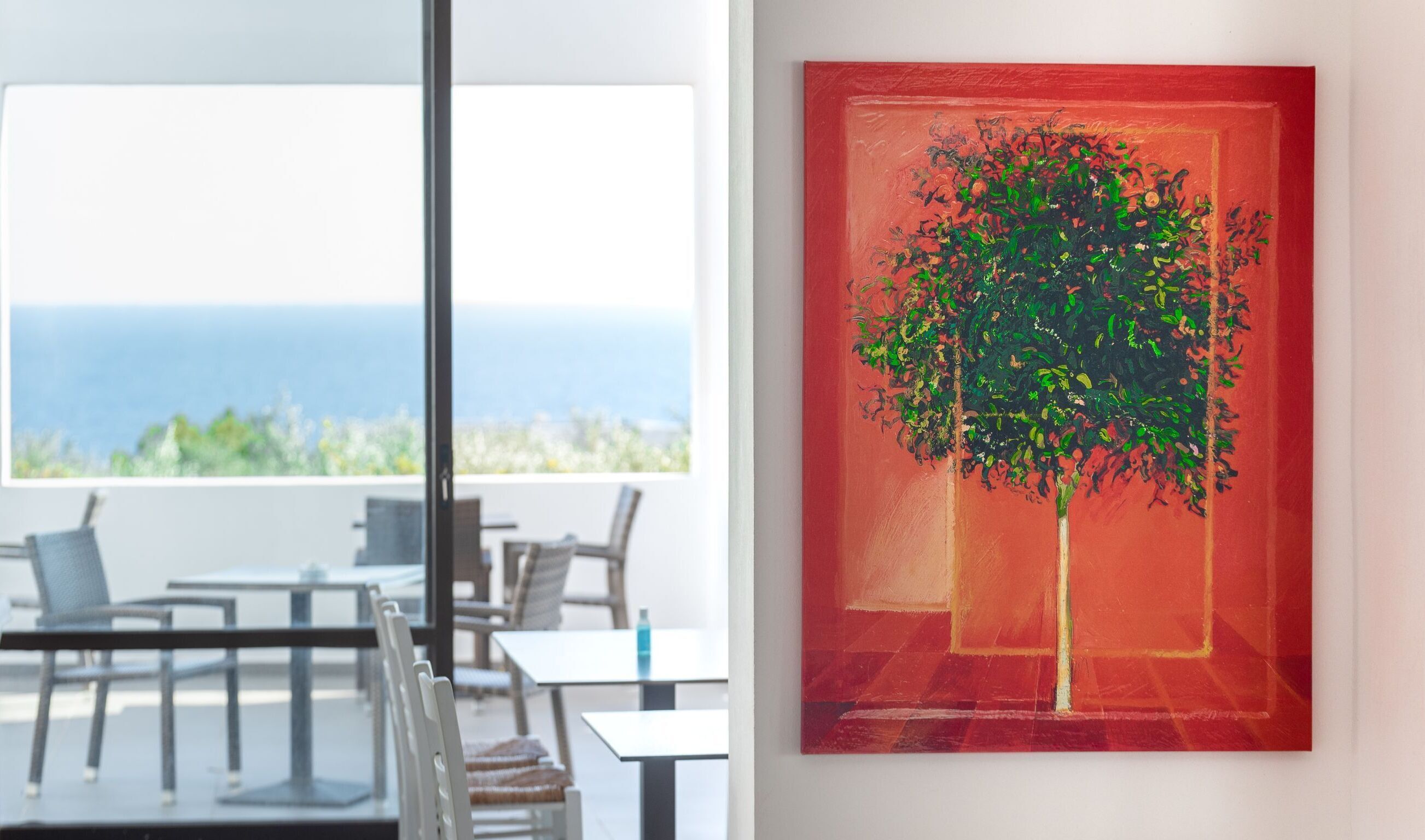 A modern dining area with a view of the sea, a table, chairs, and a glass partition.