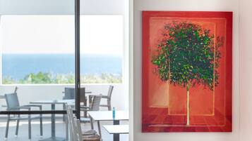 A modern dining area with a view of the sea, a table, chairs, and a glass partition.
