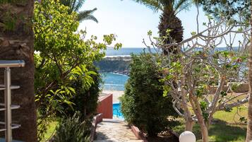 A pathway leading to a pool with a view of the sea and hills.
