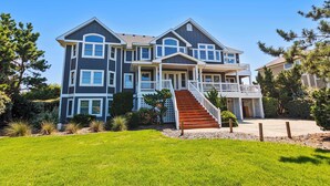 A two-story house with a front porch, a staircase, and a well-maintained lawn. - OCEANFRONT, Ocean views, ELEV, Private Pool, Private beach access, WL1083, Lighthouse Drive (Corolla)