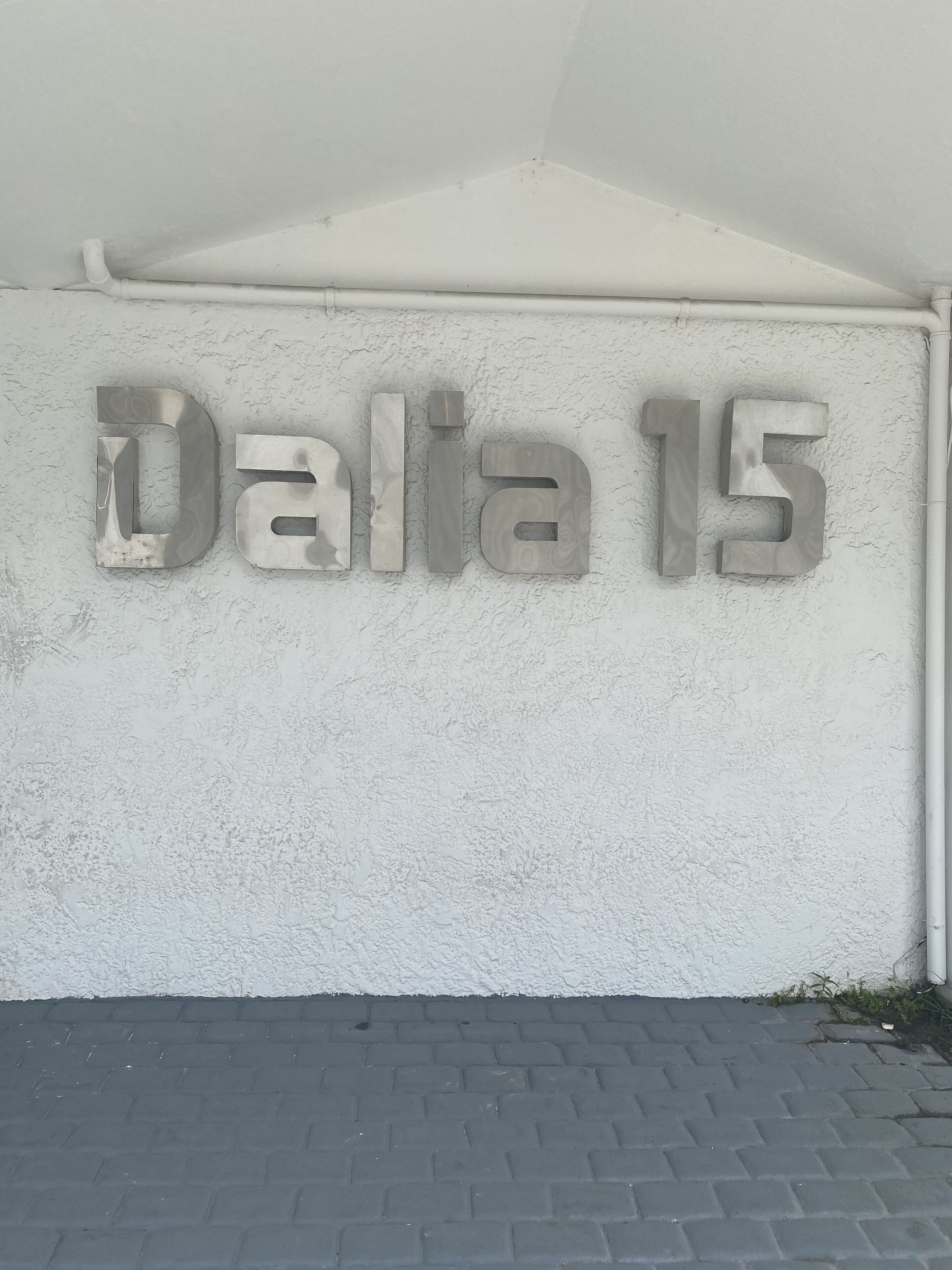 Una pared con los números "Dalia 15" en letras metálicas.