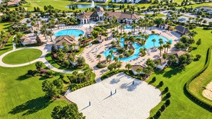 Een golfbaan met een groot centraal zwembad, omringd door perfect onderhouden gazons en palmbomen.