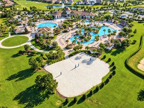 A golf course with a large central pool, surrounded by manicured lawns and palm trees. - Reunion Resort Condo: Waterpark, Clubhouses and fun! (Four Corners)