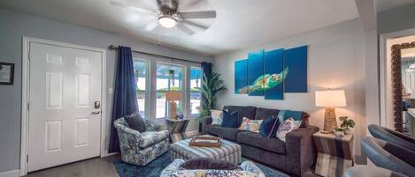 A living room with a ceiling fan, a couch, two armchairs, a coffee table, and a rug.