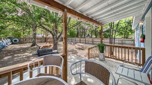 Eine überdachte Terrasse mit Gartenmöbeln, einem Grill und einem Holzboden.