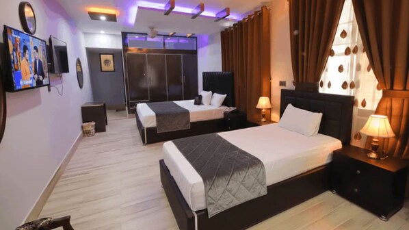 Una habitación de hotel con dos camas, televisión, armario y baño.