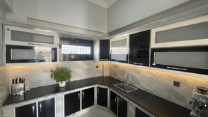 A modern kitchen with black cabinets, a marble countertop, and built-in appliances. - Khan Continental Hotel & Restaurant (Mansehra)