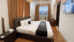 A hotel room with a large bed, a bedside telephone, a nightstand, and a view of mountains through the window. - Khan Continental Hotel & Restaurant (Mansehra)