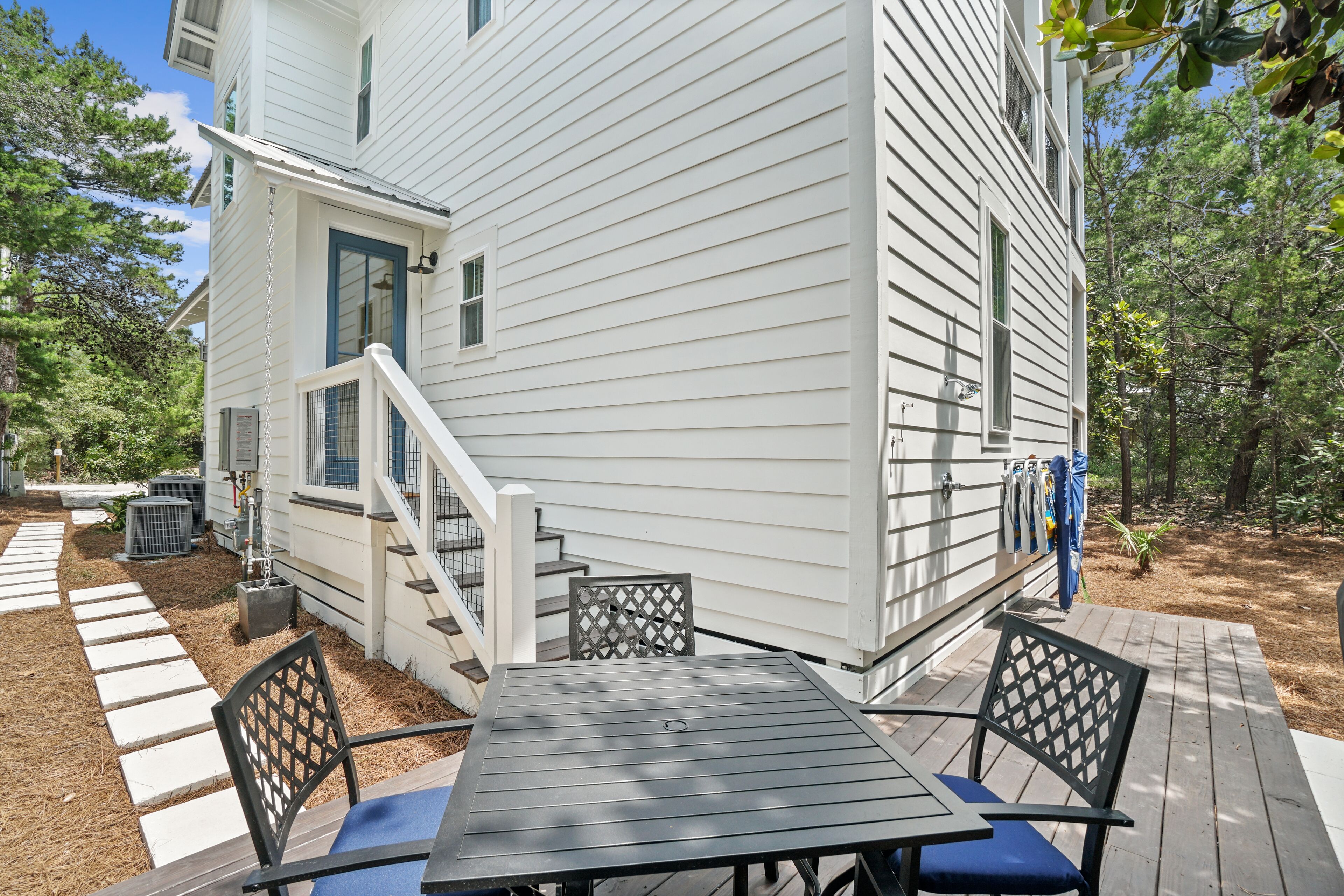 Une maison blanche avec une terrasse, une table et deux chaises.