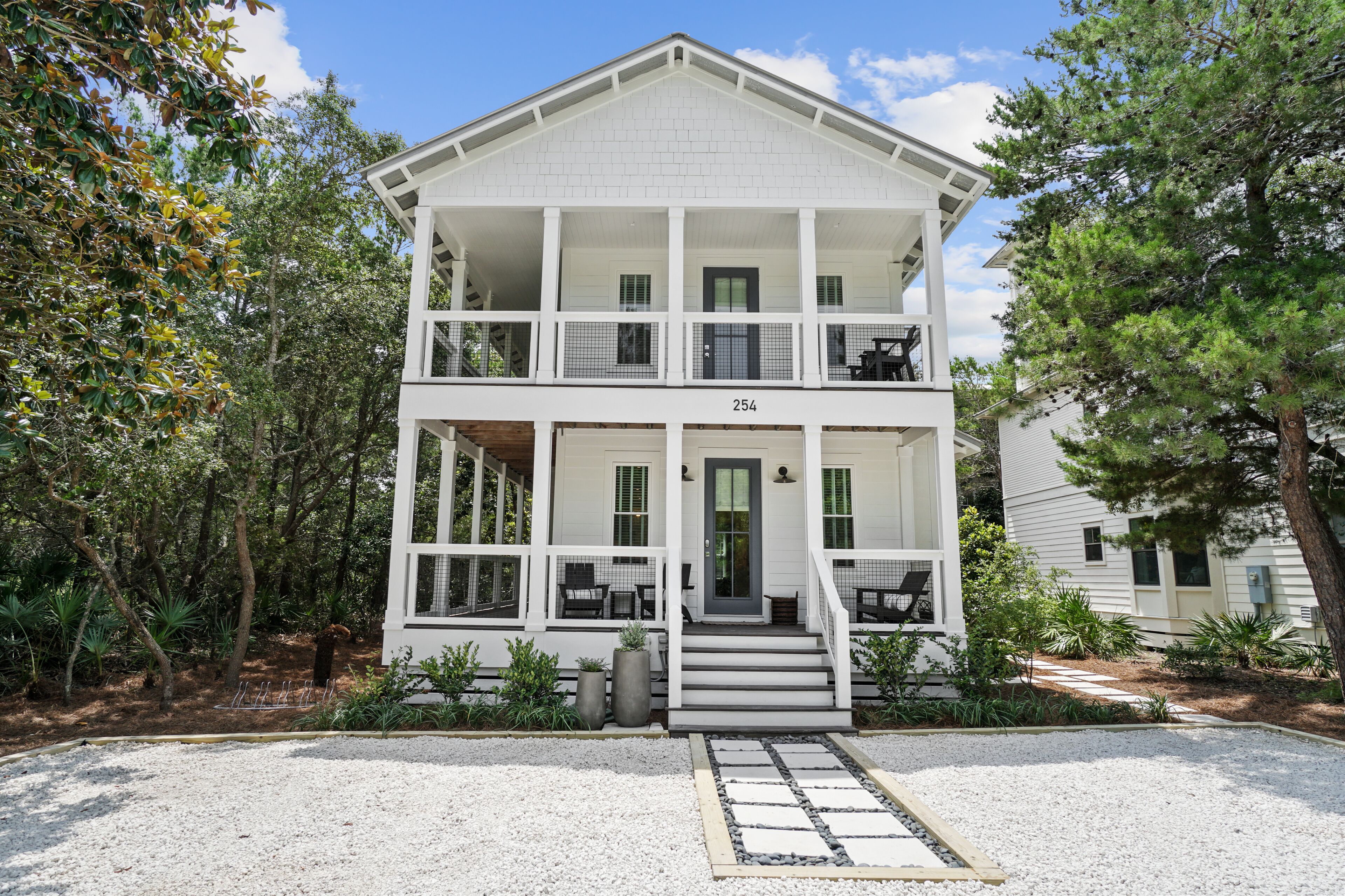 A two-story white building with a covered porch, numbered 254, surrounded by trees and a gravel driveway.