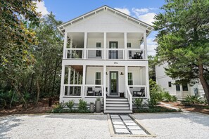 A two-story white building with a covered porch, numbered 254, surrounded by trees and a gravel driveway.