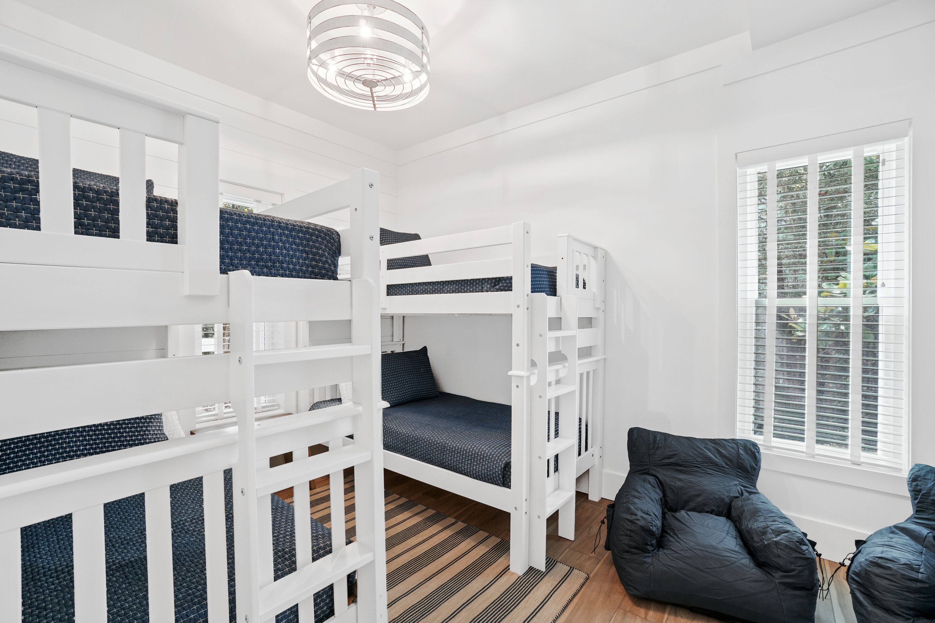 A room with bunk beds, a black chair, and a window with blinds.