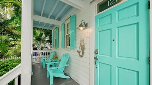 A porch with turquoise doors and shutters, a white railing, and a small table with chairs. - **ISLAND INSPIRATION @ OLD TOWN** Home & Pool + Last Key White Glove Service... (Key West)