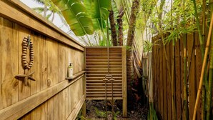 A wooden fence with a vertical slat design, a wooden bench, and a small shelf with a bottle and a star-shaped object. - **ISLAND INSPIRATION @ OLD TOWN** Home & Pool + Last Key White Glove Service... (Key West)