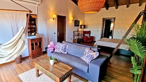 A cozy living room with a hammock, a sofa with patterned cushions, a wooden coffee table, and a potted orchid. - Casa Balimar - Pool, Jacuzzi, Internet, Garten, Meerblick (Tarajalejo)