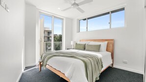 A bedroom with a bed, a ceiling fan, and large windows. - Kings Surf Unit 6, 5 Ormonde Tce, Kings Beach (Kings Beach)