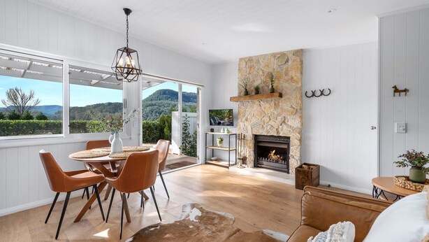 Una habitación amplia con chimenea de piedra, un área de comedor con sillas y vistas al exterior.