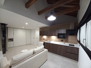 Una cocina moderna con armarios de madera, microondas integrado y encimera blanca.