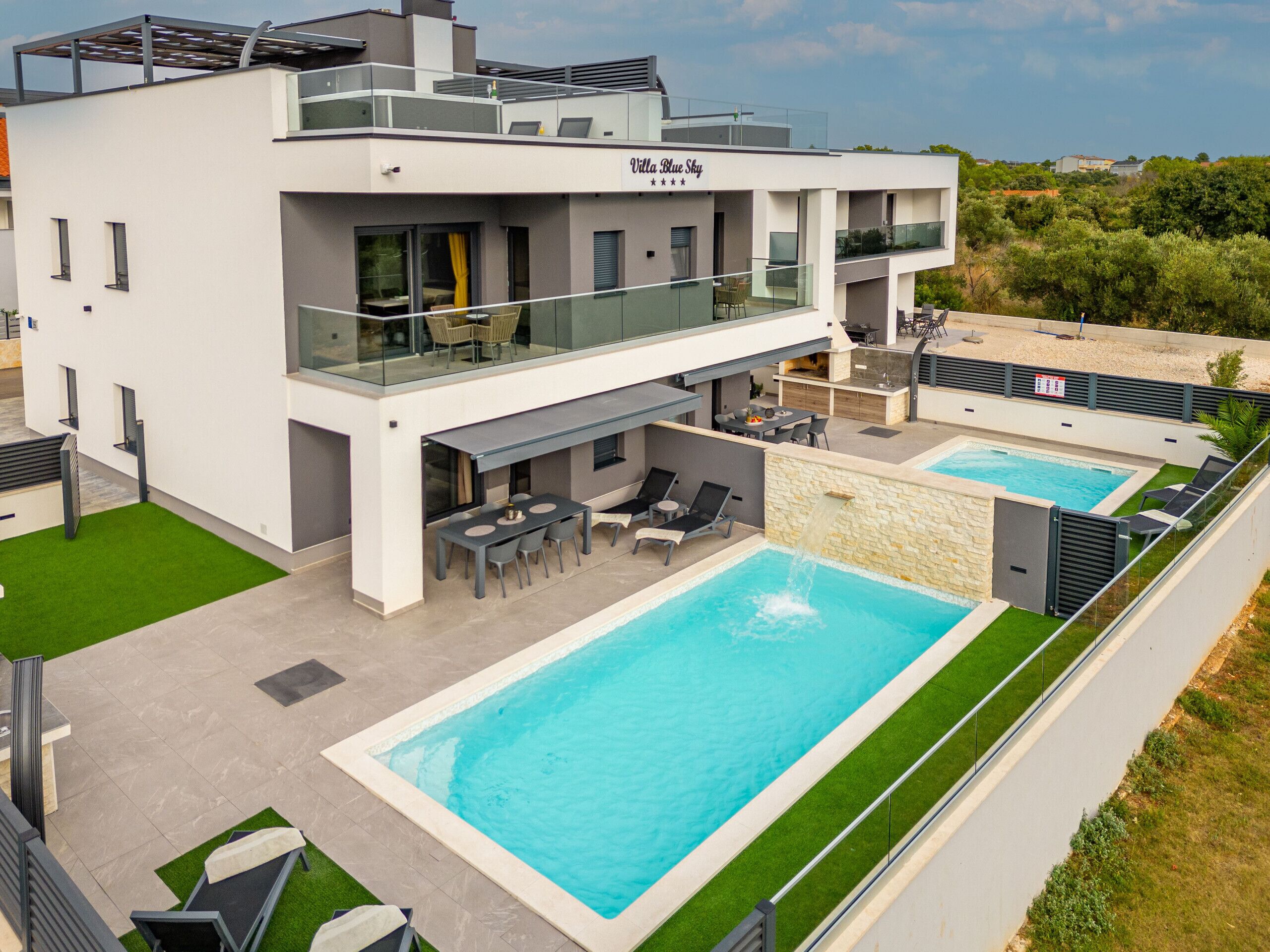 A modern villa with a rooftop terrace, a swimming pool, and a dining area.