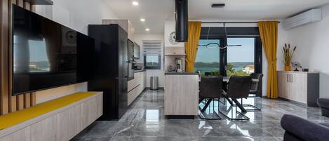 A modern kitchen with a built-in TV, a dining area with a table and chairs, and a view of the outdoors.