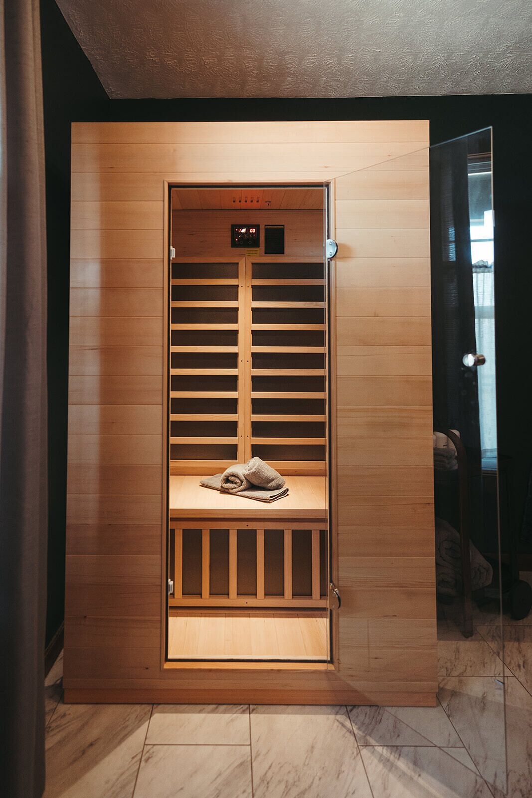 Un vestidor con estantes de madera y un banco, que incluye un panel de control digital sobre los estantes.