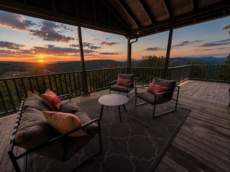 A covered outdoor seating area with a view of the sunset and mountains.. Stunning Long Range Views: Mountaintop Cabin w/ Private Sauna + Outdoor Fire Pit