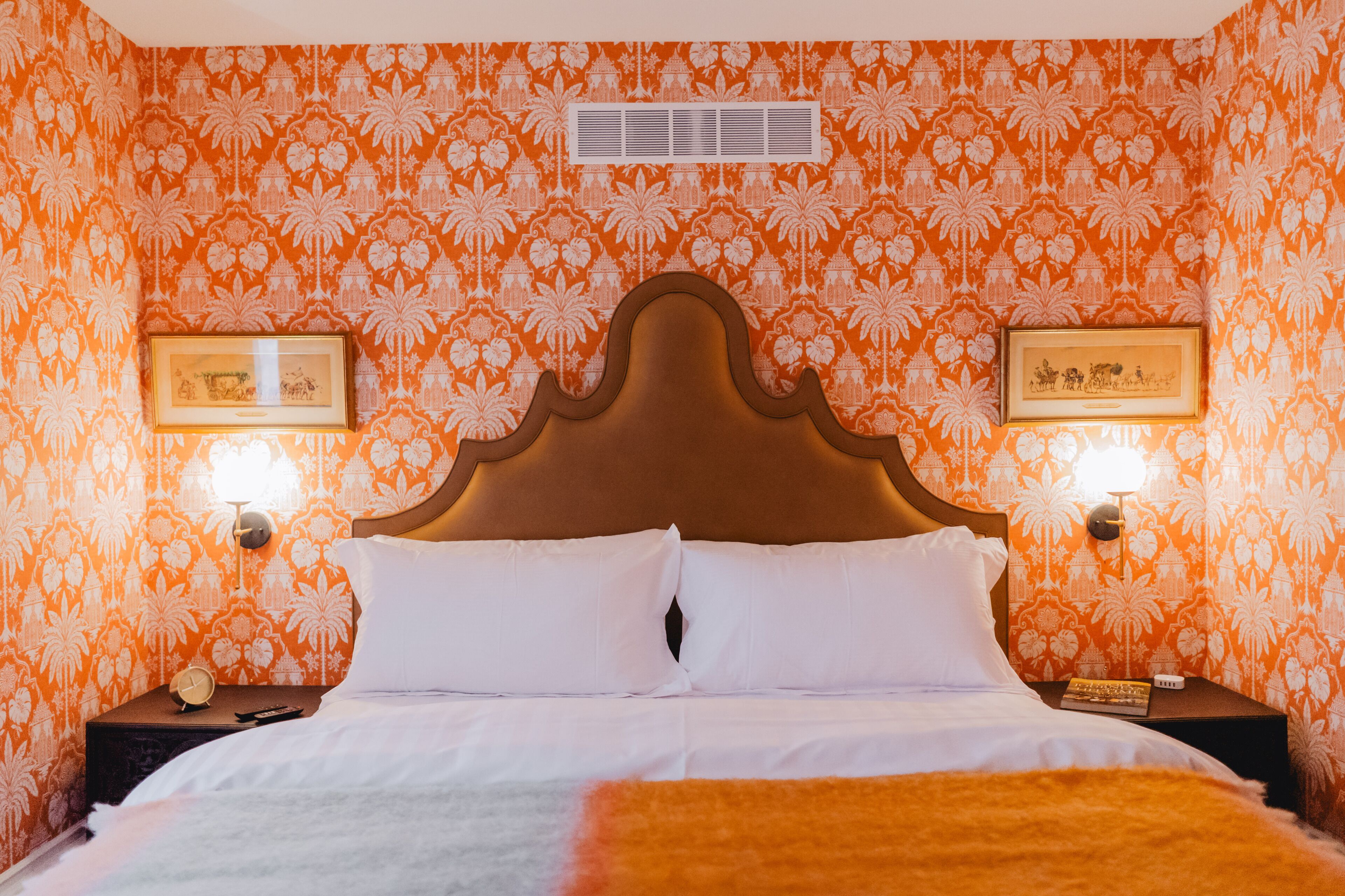 A hotel room with a large bed, two bedside tables, and a headboard.