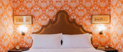 A hotel room with a large bed, two bedside tables, and a headboard.