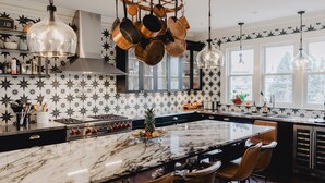 A modern kitchen with a large island, stainless steel appliances, and a star-patterned backsplash. - The Lilley Mansion Bed & Breakfast (Spring Lake)