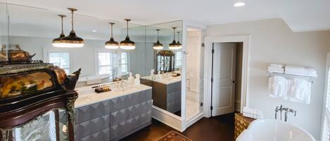 A modern bathroom with a large mirror, a freestanding bathtub, and a vanity with a geometric-patterned cabinet.