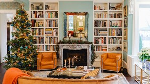 A cozy living room with a fireplace, bookshelves, and a Christmas tree. - The Lilley Mansion Bed & Breakfast (Spring Lake)