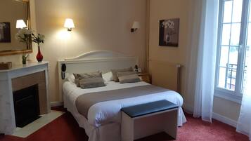 Een slaapkamer met een bed, bedlampen, een open haard en een raam.