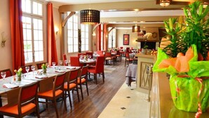 Un ristorante con pavimento in legno, sedie rosse e tavoli apparecchiati per la cena.