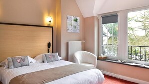 Camera da letto con un letto grande, una sedia, un termosifone, una finestra con vista e una lampada a parete.