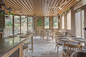 An indoor dining area with wooden ceiling beams, round tables, and chairs. - Casa Coco Boutique Hotel Spa Adults Only (Lloret de Mar)