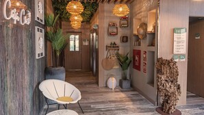Eine Hotelhalle mit Holzbalken an der Decke, einem Empfangsbereich und Sitzbereichen mit weißen Stühlen.