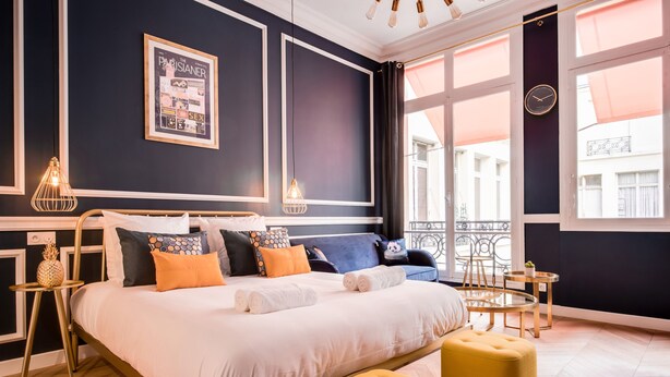 A modern bedroom with a large bed, a small table, and a chair. - The Blue Elysée (Paris)
