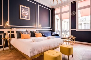 A modern bedroom with a large bed, a small table, and a chair. - The Blue Elysée (Paris)