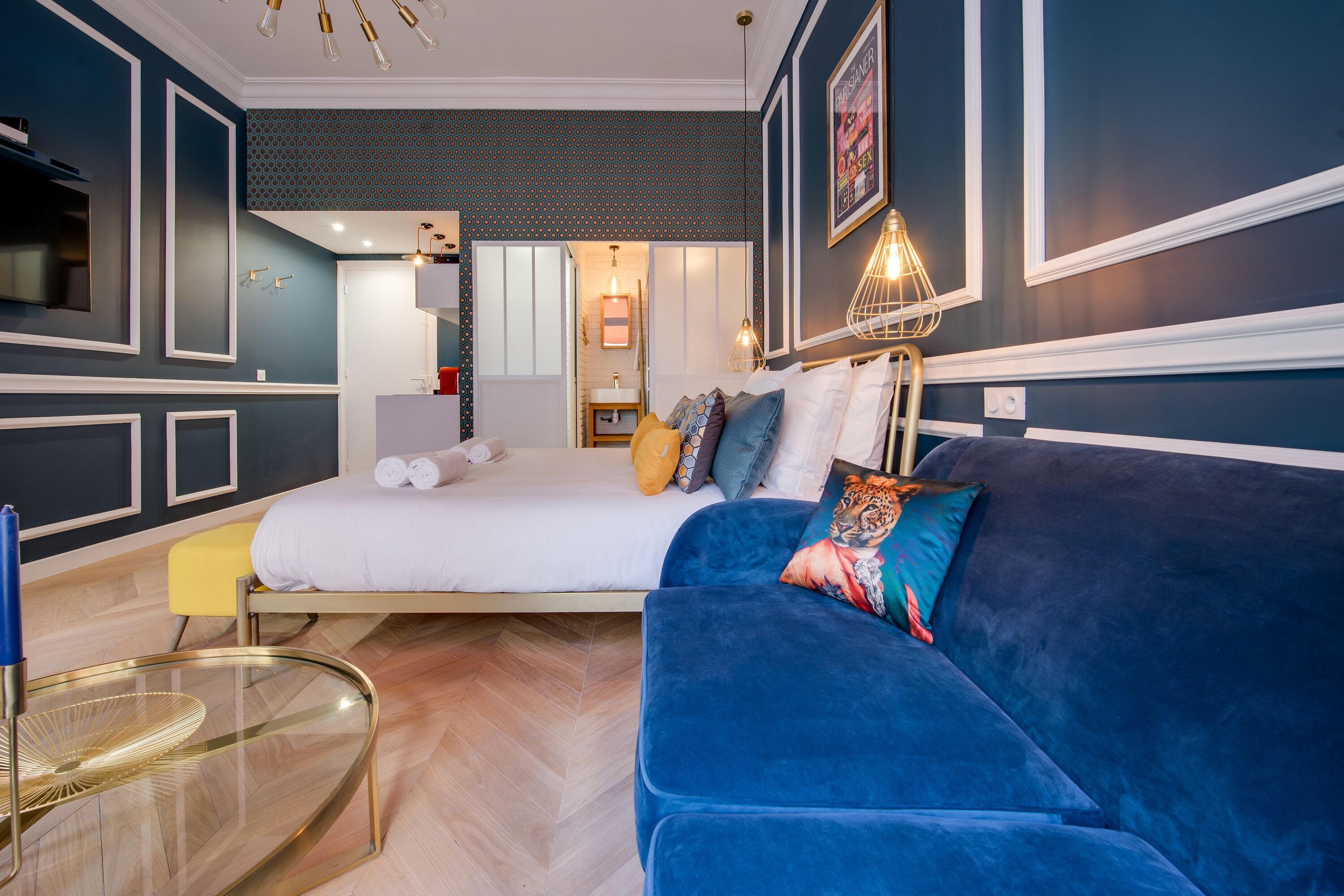 Una camera da letto moderna con un letto grande, un divano blu e un tavolino da caffè in vetro.