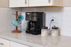 A kitchen with a coffee maker, two ceramic mugs, and a wooden mug holder. - Tierra Velo - HGTV Style in East Tucson (Tucson)