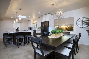 A modern kitchen with a central island, dark wooden chairs, and a chandelier. - Tierra Velo - HGTV Style in East Tucson (Tucson)