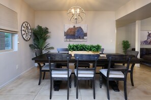A dining area with a dark wooden table and chairs, a chandelier, and a painting of a barn on the wall. - Tierra Velo - HGTV Style in East Tucson (Tucson)