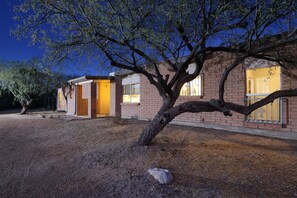 A two-story house with a brick exterior, a large tree in front, and a well-lit entrance. - Tierra Velo - HGTV Style in East Tucson (Tucson)