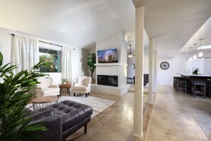 A modern living room with a fireplace, a dining area, and a kitchen in the background. - Tierra Velo - HGTV Style in East Tucson (Tucson)